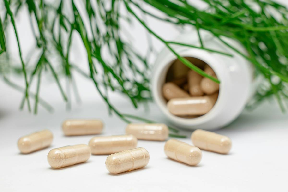 Red clover isoflavone cure in capsule form beside fresh red clover blossoms