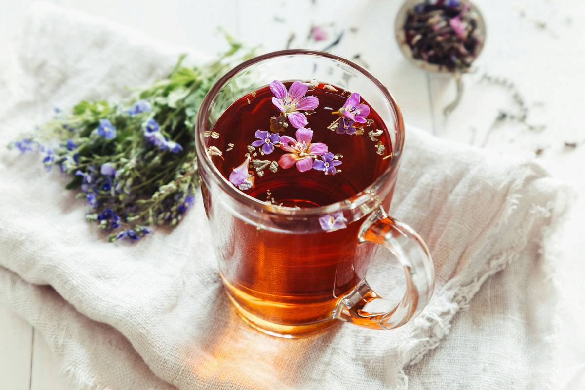 natural hot flash solution: woman sipping red clover tea while journaling about menopause symptoms